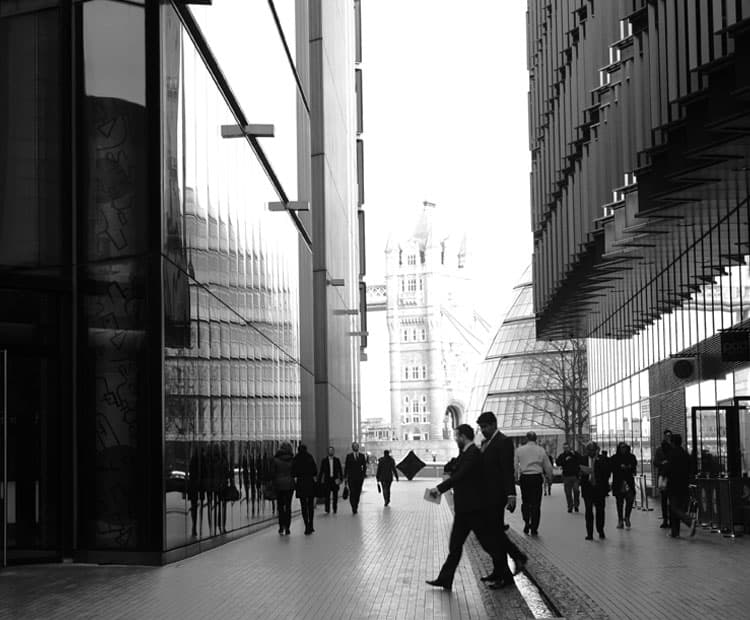 Black and white image of business people surrounded by high rise buildings.